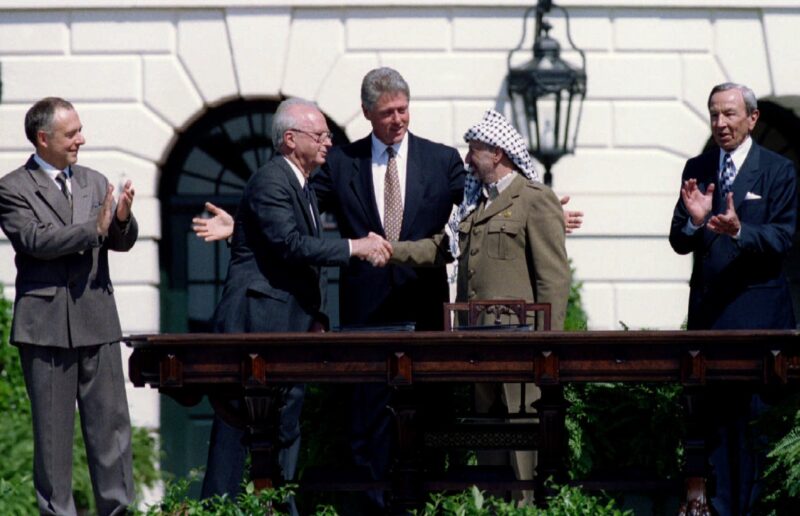 President Clinton brings Israeli Prime Minister Yitzhak Rabin (L) and PLO Chairman Yasser Arafat together for an historic handshake after the signing of the Israeli-PLO peace accord at the White House Sept. 13. Arafat extended his hand first to Rabin. Russian Foreign Minister Andrei Kozyrev (left) and US Secretary of State Warren Christopher applaude the handshake - PBEAHUNJZCM